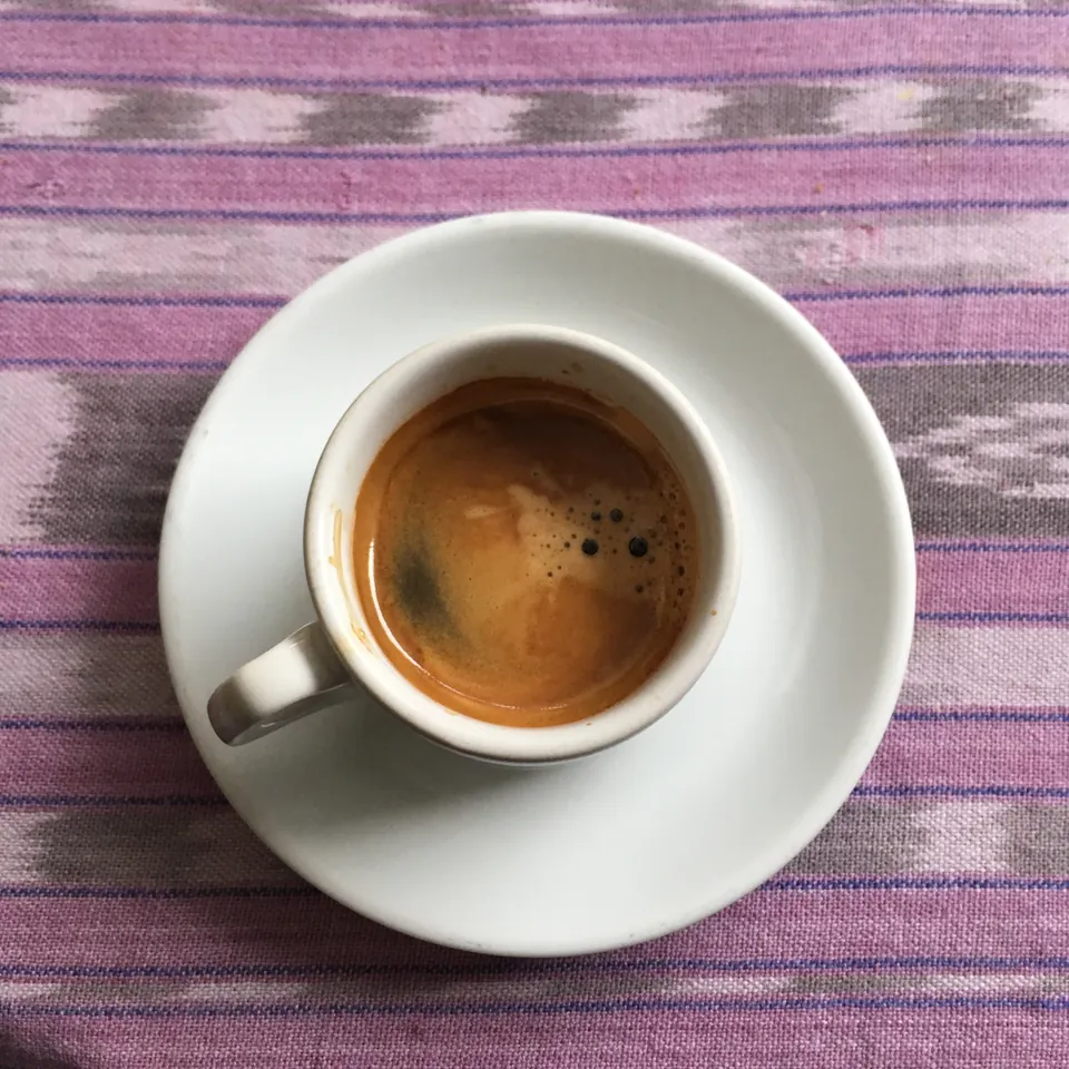 Espresso en una taza blanca sobre un tejido estampado.