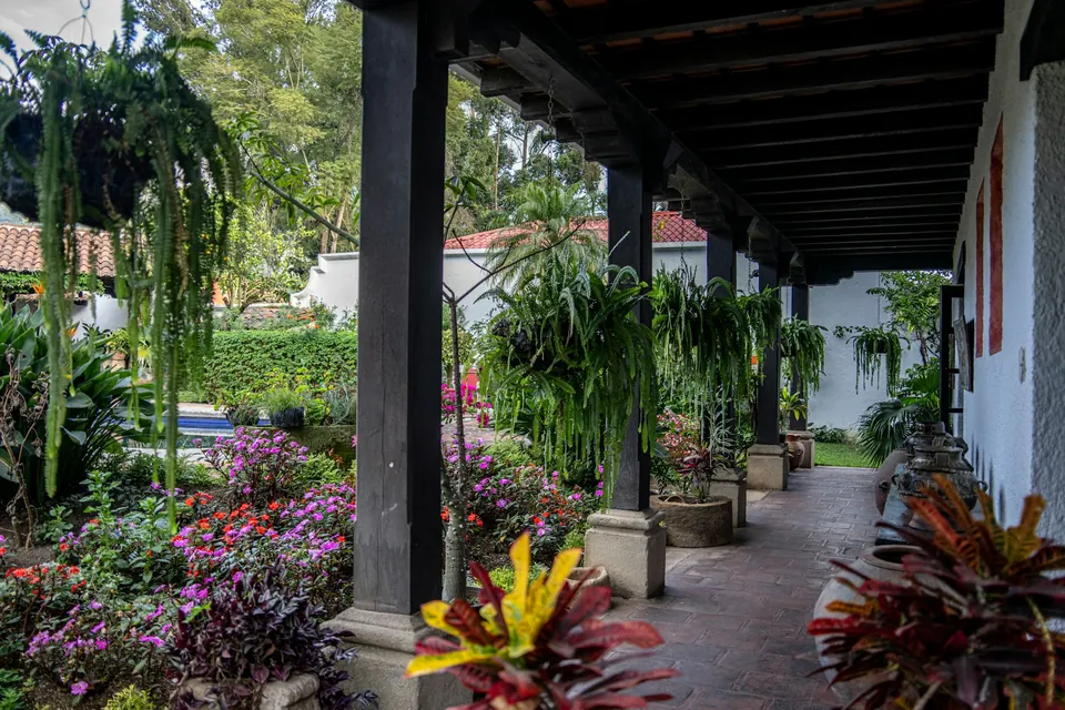 Corredor sombreado junto a un patio con vegetación en Antigua Guatemala.
