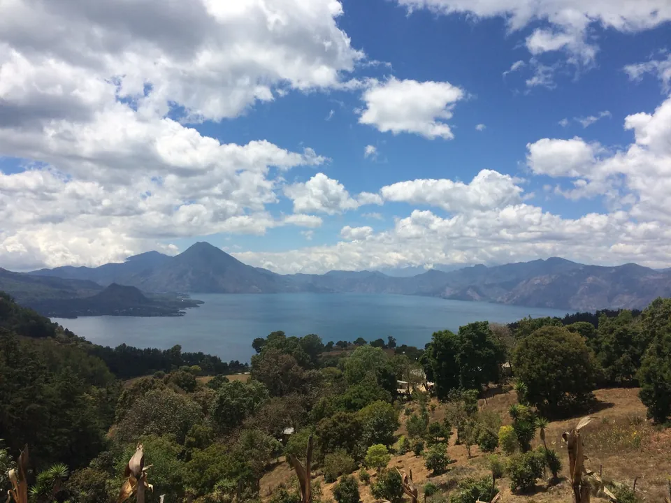 Lago y paisaje volcánico de Guatemala bajo un cielo azul.